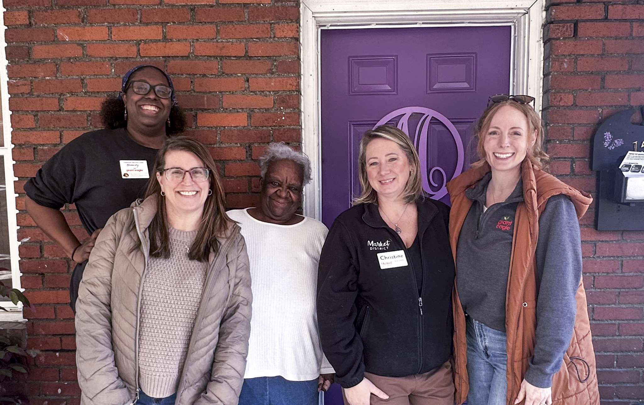 Photo of volunteeres from Giant Eagle standing on a homeowner's porch after delivering a food donation